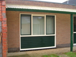 Garage deur vervangen voor een kozijn met borstwering van stapel schrootjes panelen, 2 draaikiep ramen en een ventilatie rooster.