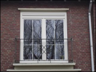 Stolpraam naar binnendraaiend met kalfrooster boven de ramen. Ongelijke Roeden in het glas